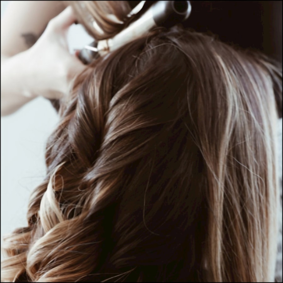 A client having her long dark hair styled at the chair