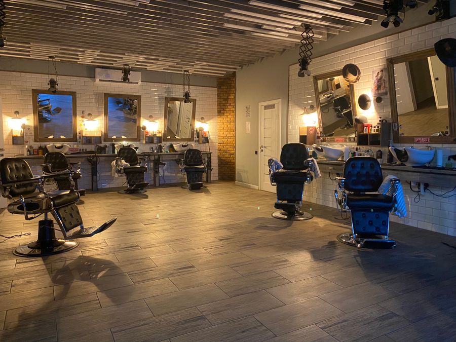 The men's grooming chairs — barber stations and mirrors under warm bulb lighting