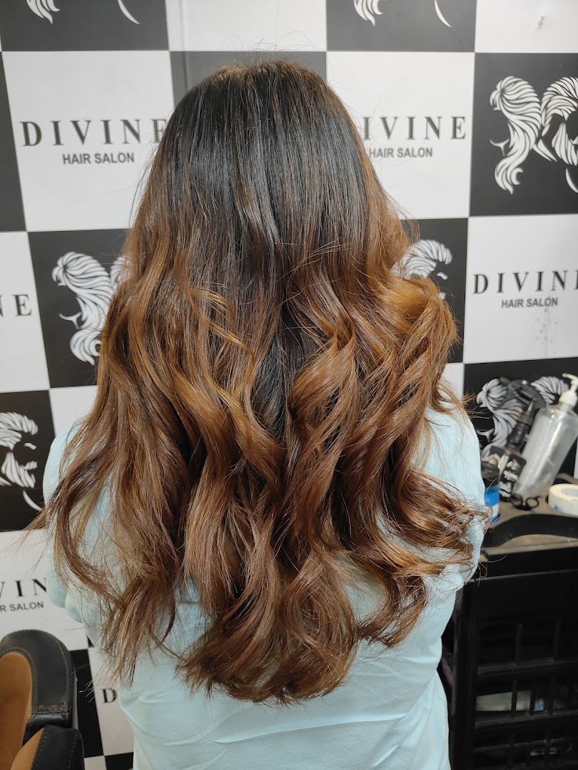 Copper balayage long waves in front of the salon's signature wall