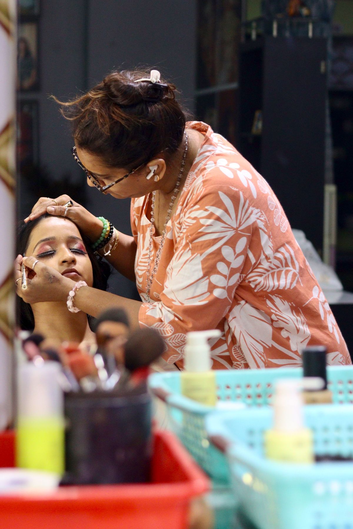 A makeup artist working close-up on a client's eye makeup at a salon station.