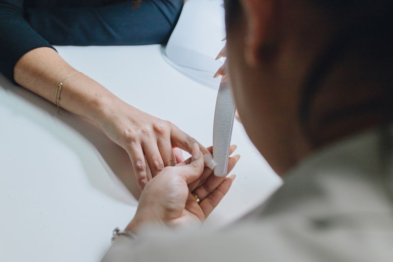 A manicurist shaping a client's nails at the nail bar.