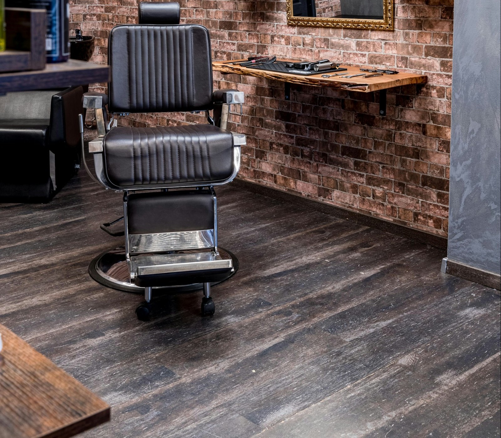 A styling chair beside a live-edge wooden station against exposed brick