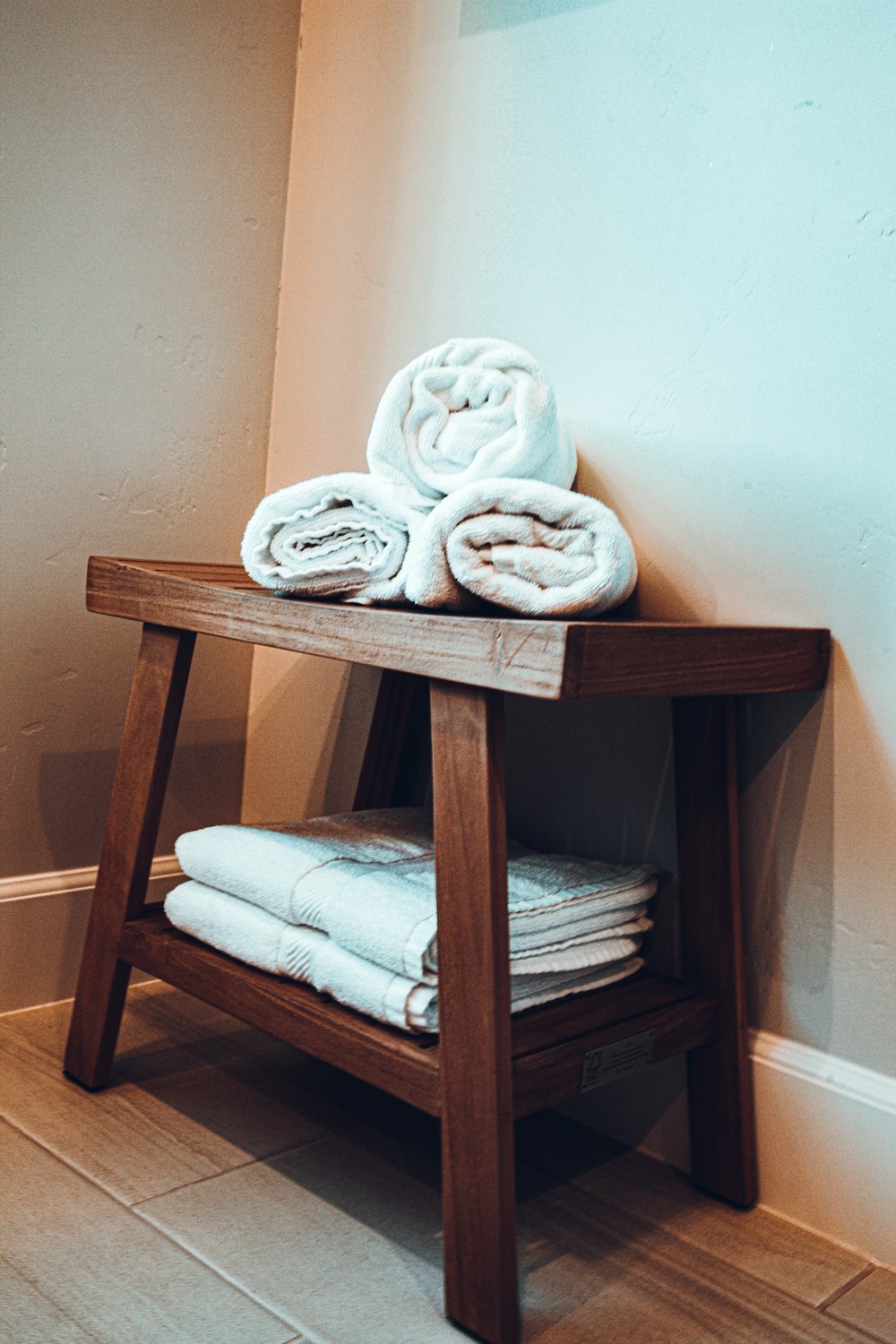 Rolled white towels stacked on a dark wood bench