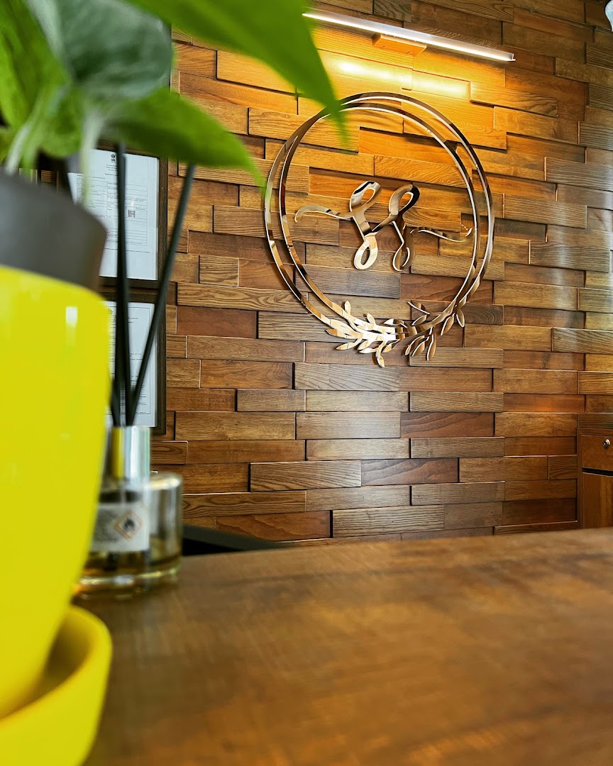 The polished-steel Salon Stories monogram mounted on the wood-slat wall behind reception