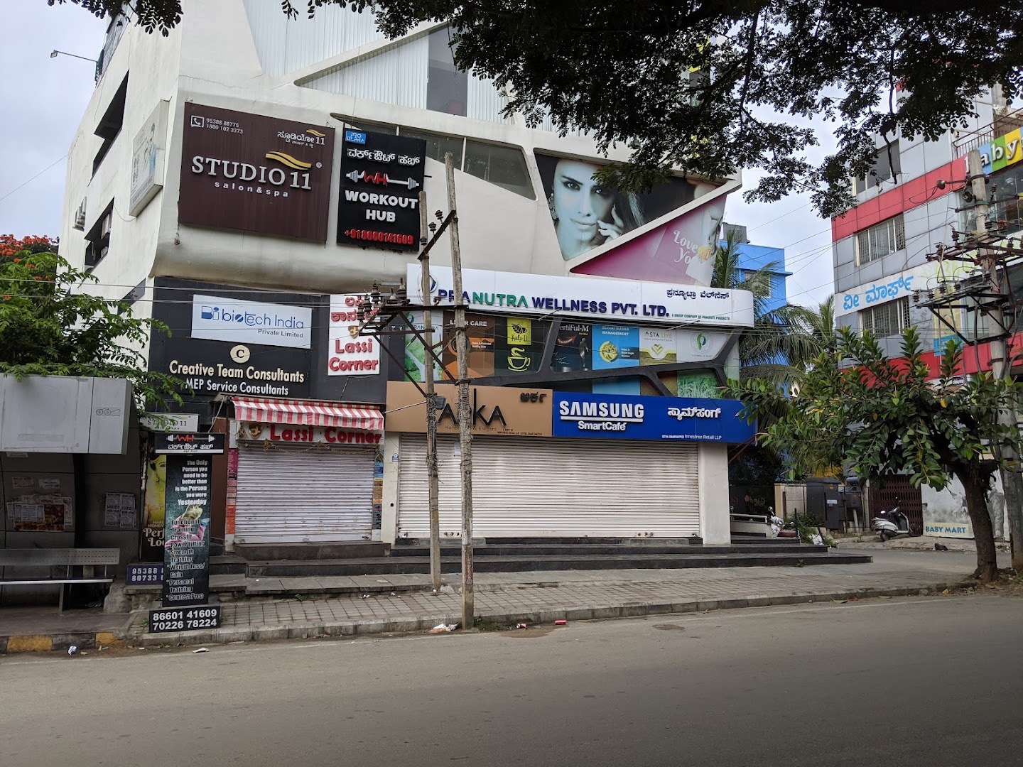 The Pavithra Paradise building on 4th Main Road; the STUDIO 11 board sits on the top floor, above Lassi Corner.