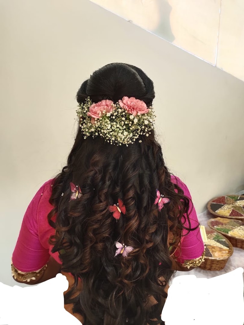 Bridal hair by STUDIO@11: a low braided bun set with fresh baby's-breath and pink roses.