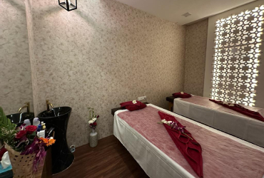 A couple's room at White Pearl Wellness with two beds dressed in blush and wine linen beside a backlit lattice screen