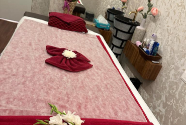 A treatment bed set with folded wine towels and fresh flowers