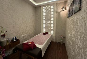 A private treatment room at White Pearl Wellness, Kalyani Nagar — a made bed in blush linen beside a backlit lattice screen