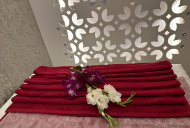 Folded wine-red towels with orchids in front of a lit lattice screen